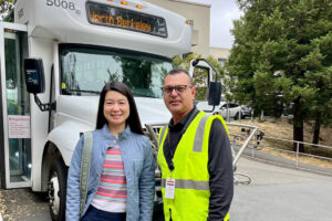 two people standing in front of a shuttle bus